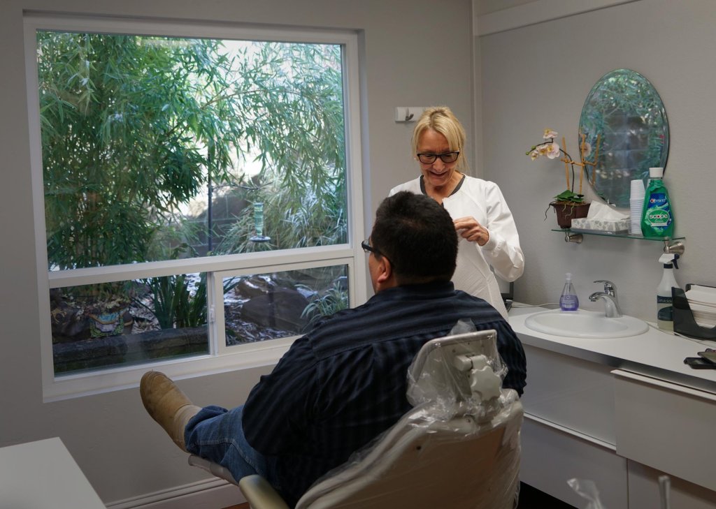 Dental assistant working with patient in operatory room at Dr. Falvey's practice