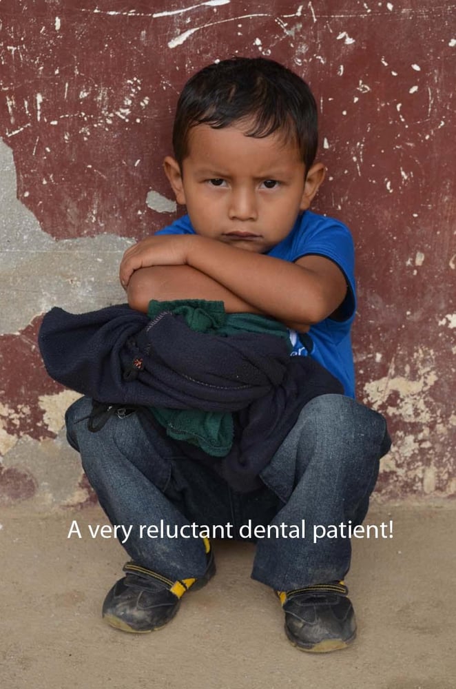 A child sitting with their arms crossed and scowling during a Honduras Mission trip